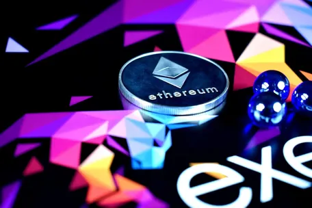 A silver coin with 'ethereum' written on it, surrounded by vibrant, warm colors.