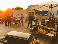 Predominantly male people chatting on a roof terrace in small groups at sunset