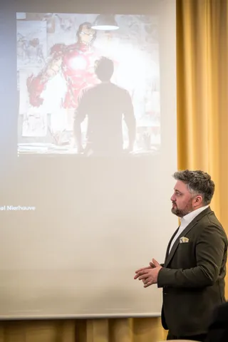 Daniel Nierhauve von 9elements bei seinem Talk beim KI Innovationsforum vor seiner Präsentation, auf der Tony Stark mit Iron Man zu sehen ist.