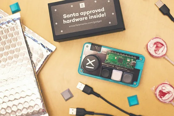 Material von GiftRush, dem Weihnachtsspiel von 9elements. Zu sehen ist die Verpackung des Spiels, zwei Lollipops, USB-Kabel sowie das selbst gebaute Pad.