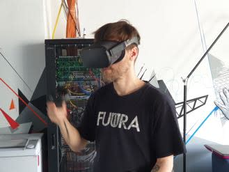 Ein Mann trägt eine VR Brille. Im Hintergrund steht ein Server.