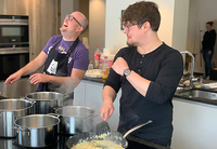 Zwei Männer stehen gut gelaunt in der Küche und kochen gemeinsam.
